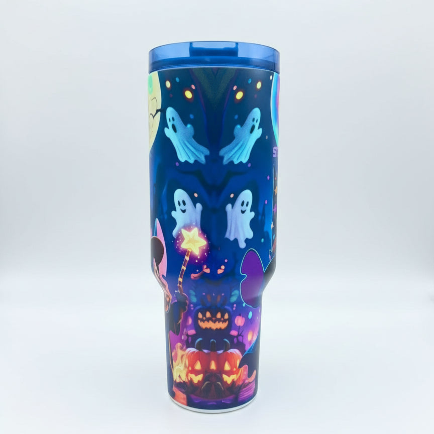 Colorful tumbler with Halloween designs on a striped table outdoors.